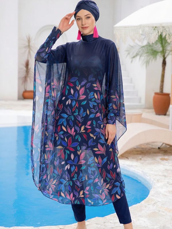 Burkini hijab bleu marine à feuilles multicolores, manches cape en voile et bonnet-turban, vue de face au bord d'une piscine