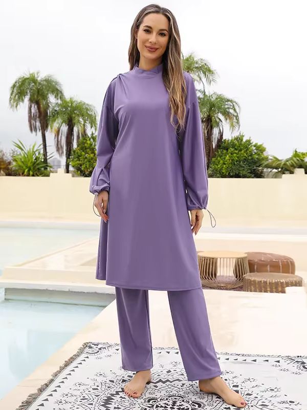 Femme vêtue d&#39;un burkini violet, debout près d&#39;une piscine dans un cadre extérieur