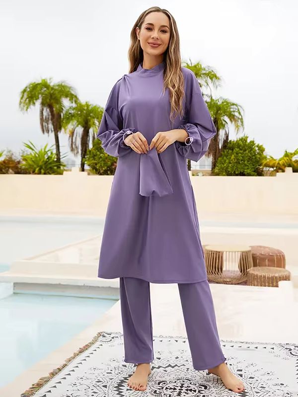 Femme portant un burkini violet trois pièces, vue de dos près d'une piscine