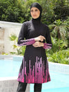 Une femme porte un burkini noir orné de motifs graphiques roses sur le bas de la tunique et les manches. La tenue est complétée par un hijab noir parfaitement assorti. Elle se tient debout près d&#39;une piscine, dans un environnement verdoyant, affichant une allure à la fois élégante et moderne, alliant confort et style.