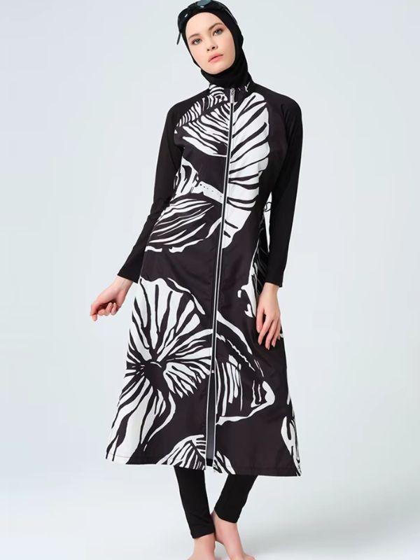Burkini long noir à grandes feuilles blanches, glissière centrale et col montant, vue de face sur fond gris