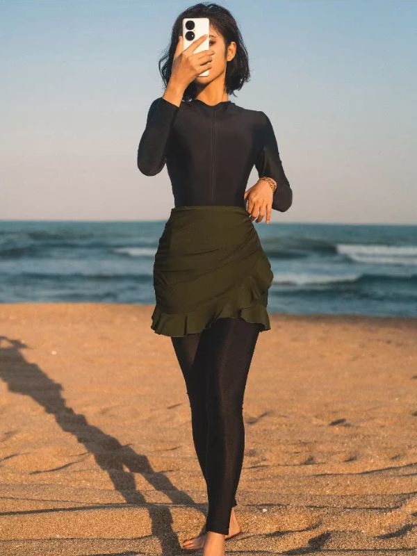 Femme portant un burkini noir avec une jupe kaki sur une plage