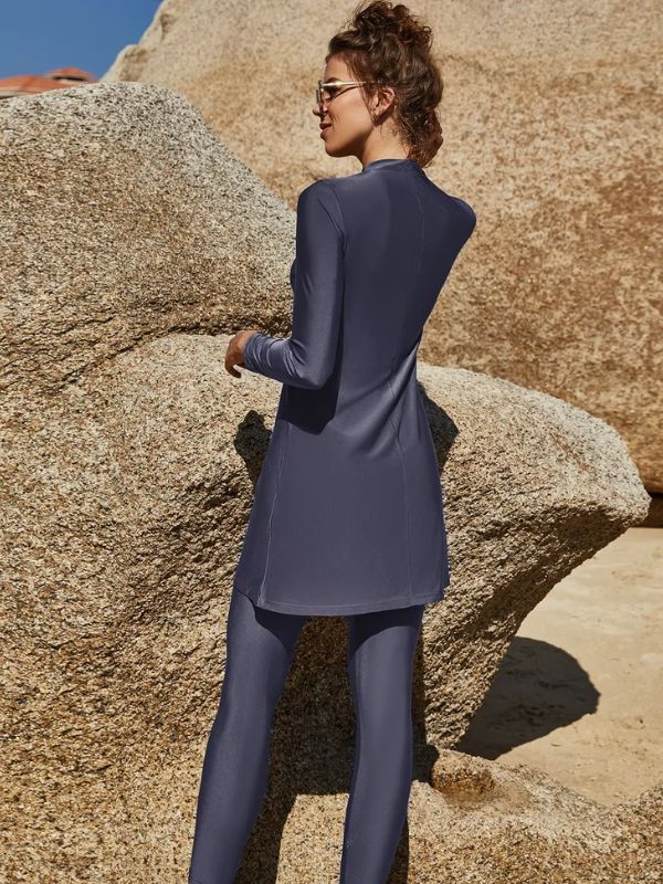 Vue arrière d&#39;un burkini bleu porté par une femme sur une plage rocheuse