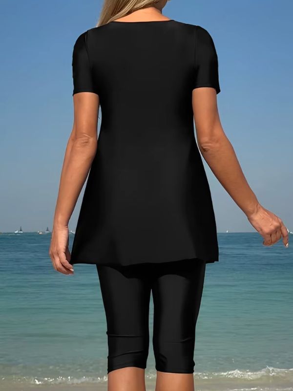 Dos du burkini manche courte noir, tunique unie évasée et legging noir, vue de dos sur la plage
