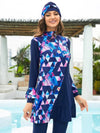 Une femme souriante porte un burkini bleu marine avec un motif géométrique audacieux de triangles roses et bleus, accentué de motifs floraux éclatants. La coupe élégante de la tenue, rehaussée par un volant subtil à l&#39;ourlet, lui confère une allure à la fois moderne et féminine. Le turban assorti, décoré des mêmes motifs, complète harmonieusement l&#39;ensemble, encadrant son visage avec style. Elle se tient près d&#39;une piscine, ajoutant une touche de fraîcheur et de vacances