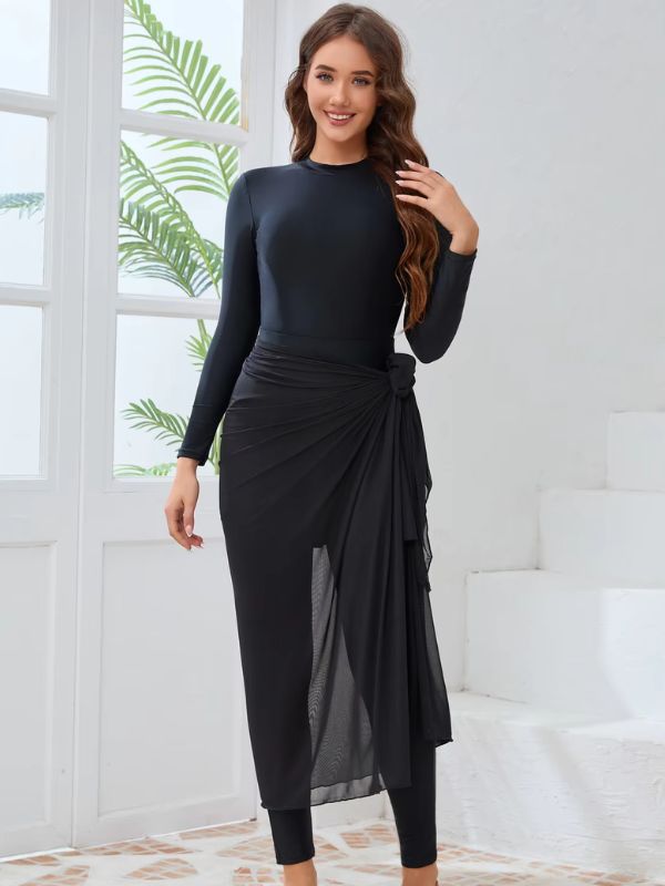 Une femme en burkini noir complète son allure avec un chapeau en paille