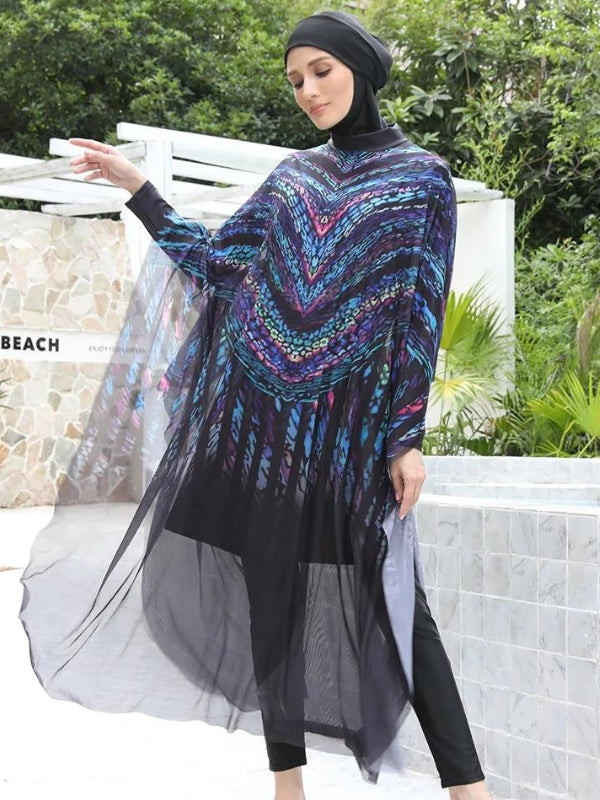 Une femme porte un burkini noir orné de motifs en chevron multicolores, accentués par des nuances vibrantes qui attirent le regard vers le haut de sa silhouette. Une cape transparente et fluide enveloppe l'ensemble, ajoutant une touche d'élégance aérienne à sa tenue. Le tissu léger de la cape semble flotter autour d'elle, créant un mouvement gracieux à chacun de ses gestes, tandis que son expression sereine complète l'harmonie de l'ensemble