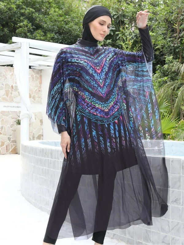 Une femme porte un burkini noir orné de motifs en chevron multicolores, accentués par des nuances vibrantes qui attirent le regard vers le haut de sa silhouette. Une cape transparente et fluide enveloppe l'ensemble, ajoutant une touche d'élégance aérienne à sa tenue. Le tissu léger de la cape semble flotter autour d'elle, créant un mouvement gracieux à chacun de ses gestes, tandis que son expression sereine complète l'harmonie de l'ensemble