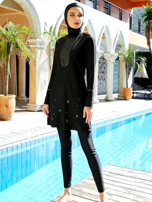 Une femme en burkini noir devant une piscine magnifique