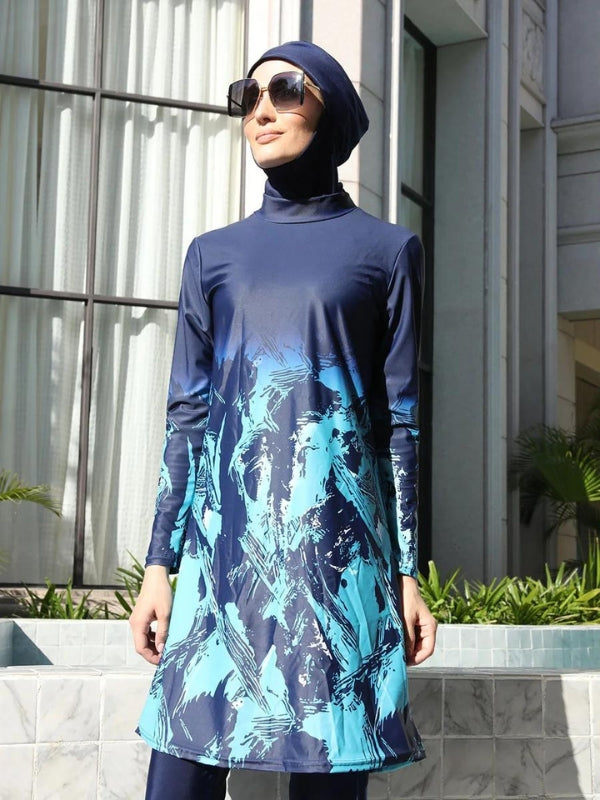 Une femme porte un burkini bleu marine orné de motifs abstraits dans des tons de bleu plus clair. Le design, qui s'étend des manches jusqu'à l'ourlet de la tunique, crée un effet dynamique et moderne. Le hijab assorti et de grandes lunettes de soleil complètent cette tenue, offrant à la fois protection et style. Elle se tient avec assurance, le cadre élégant en arrière-plan mettant en valeur la sophistication de l'ensemble