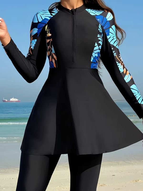 Burkini sport noir, gros plan sur la glissière et sur les panneaux de feuilles bleues et orangées des manches raglan