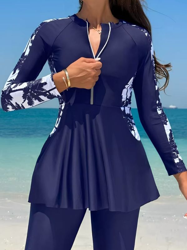 Burkini sport bleu marine, gros plan sur la glissière à ruban blanc et sur les manches raglan à palmiers blancs