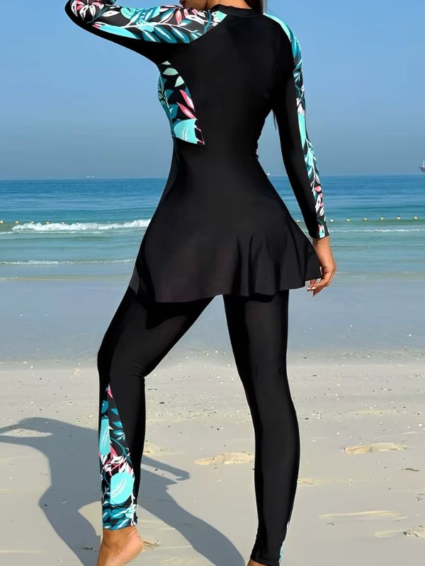 Dos du burkini sport noir à feuillages turquoise et roses, bande imprimée sur la jambe du pantalon, vue de trois quarts