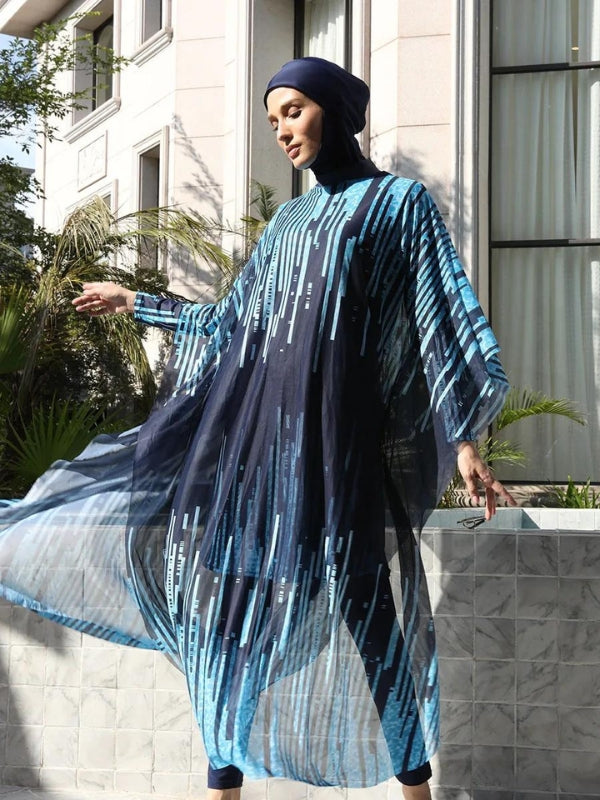 Une femme porte un burkini bleu marine orné de motifs géométriques bleus. La tenue est rehaussée par une cape transparente qui s'harmonise avec le burkini, flottant doucement autour d'elle. Le cadre élégant, avec des bâtiments modernes et une végétation verdoyante en arrière-plan, souligne l'allure à la fois sophistiquée et contemporaine de cette tenue. La femme est capturée dans un mouvement gracieux, ajoutant une touche de dynamisme à l'ensemble