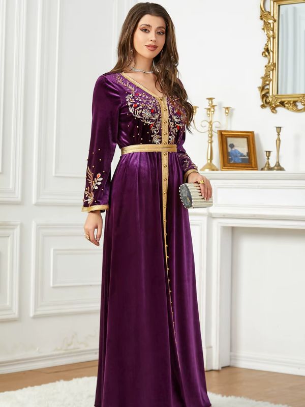 Une femme porte un caftan en velours améthyste avec des manches longues