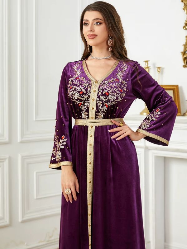 Une femme habillée d’un caftan améthyste, posé dans un intérieur raffiné