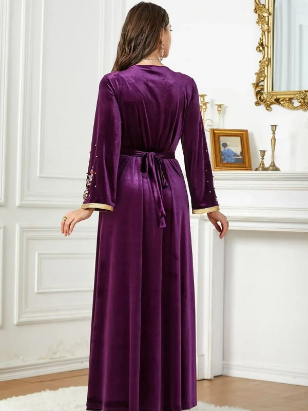 Une femme portant un caftan améthyste fluide, brodé de motifs floraux