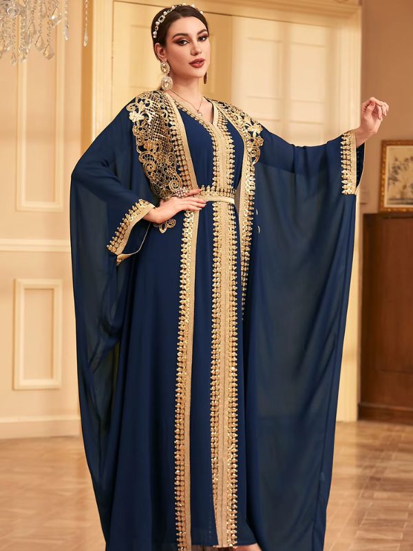 Une femme vêtue d'un caftan bleu nuit fluide et orné de broderies dorées