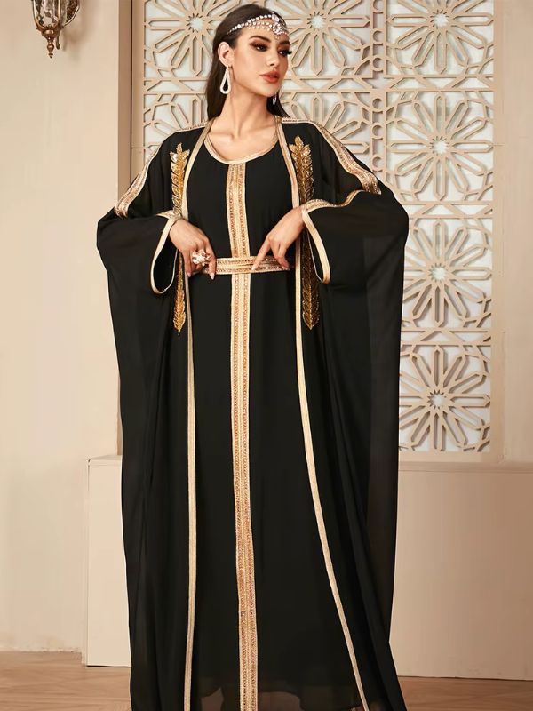 Femme levant légèrement les bras dans un caftan noir fluide