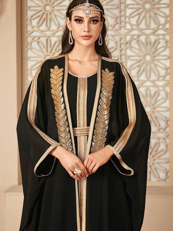 Femme portant un caftan noir orné de motifs dorés luxueux