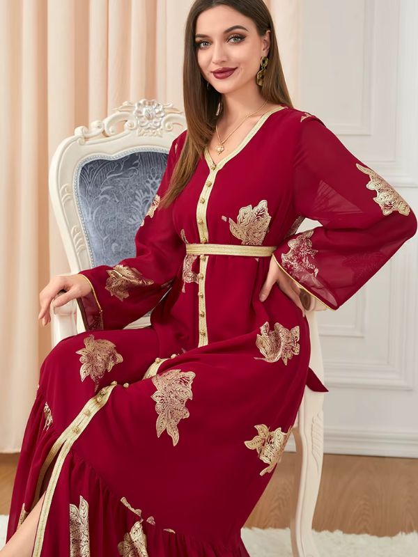 Une femme assise portant un caftan rouge à motifs dorés