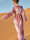 Une femme de dos porte un caftan rose