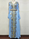 Un caftan bleu clair richement décoré de motifs dorés qui ornent la partie centrale et les manches de la tenue. La ceinture assortie, ornée de détails dorés et de pompons, cintré la taille, mettant en valeur la silhouette. Le tissu léger et fluide du caftan descend gracieusement jusqu&#39;au sol