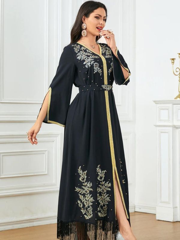 Une femme se tient de profil et porte un caftan noir et doré