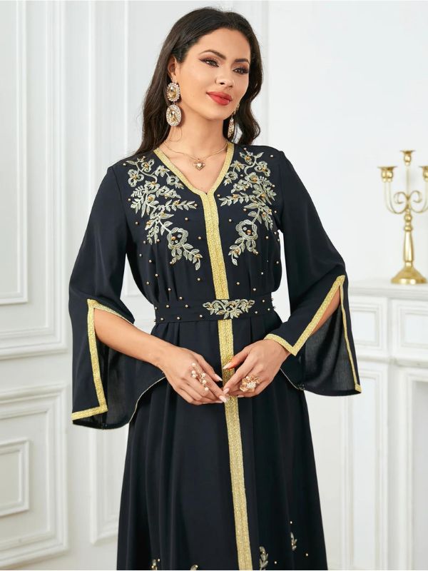 Vue rapprochée d&#39;une femme qui se tient les mains et porte un caftan noir et doré