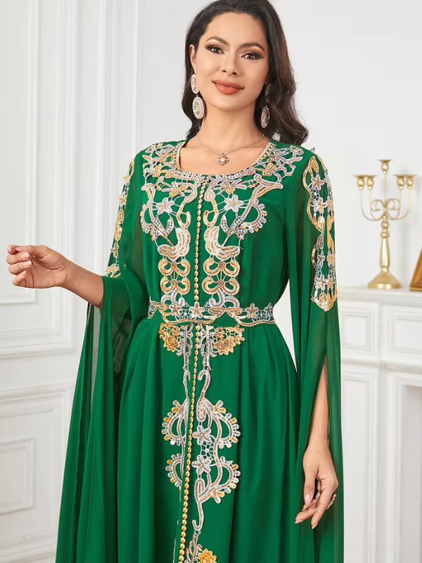 Une femme porte un caftan vert émeraude avec des broderies délicates et des ornements dorés