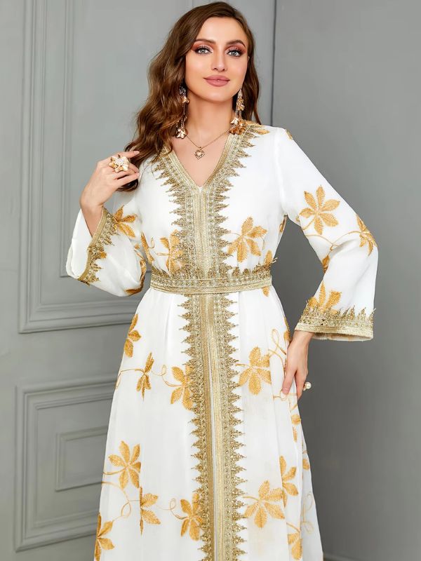 Vue de face d'une femme qui porte un caftan de mariage blanc aux motifs fleurs