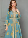 Vue rapprochée sur une femme qui porte un caftan de mariage bleu aux motifs floraux en or