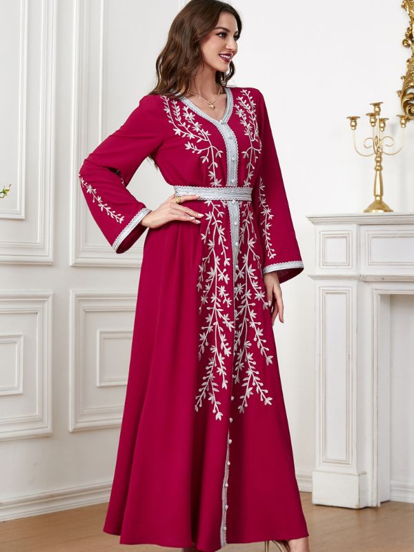 Femme qui se tient la hanche dans intérieur sublime et porte un caftan rouge