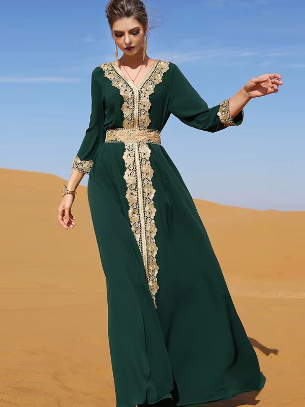 Une femme marche gracieusement dans un désert, vêtue d'un somptueux caftan vert émeraude orné de broderies dorées raffinées