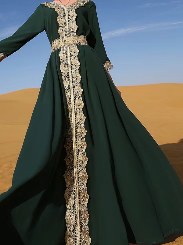 Une femme marche gracieusement dans un désert, vêtue d'un somptueux caftan vert émeraude orné de broderies dorées raffinées