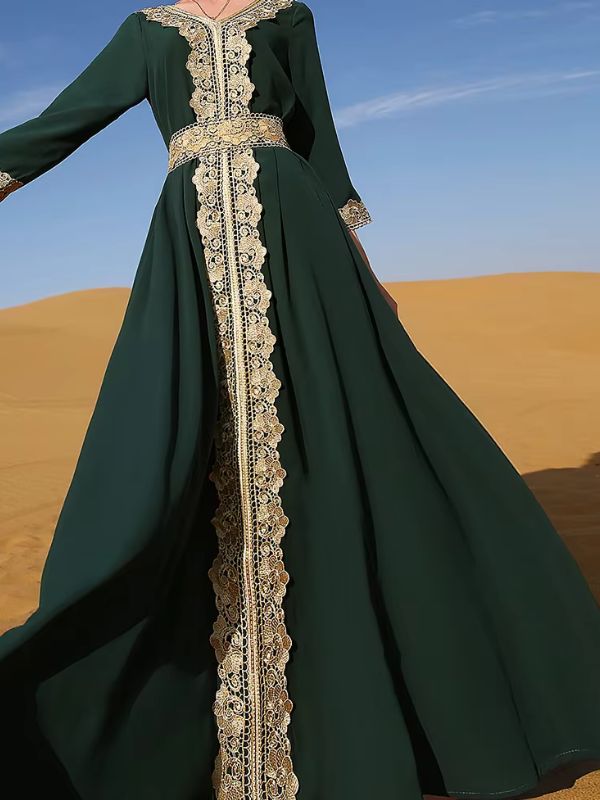 Une femme marche gracieusement dans un désert, vêtue d'un somptueux caftan vert émeraude orné de broderies dorées raffinées