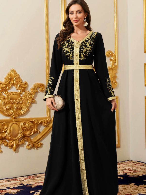 Une femme se tient de face avec un sublime caftan noir aux broderies or