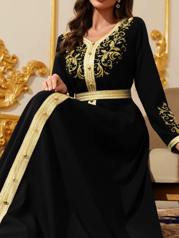 Femme assise portant un caftan marocain noir à broderies dorées arabesques