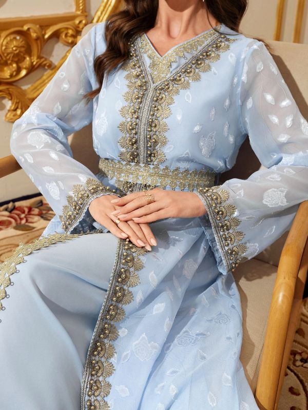 Femme portant un caftan marocain bleu ciel, gros plan sur les broderies dorées et perlées
