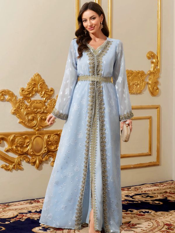 Femme portant un caftan marocain bleu ciel brodé d'or, pochette scintillante à la main