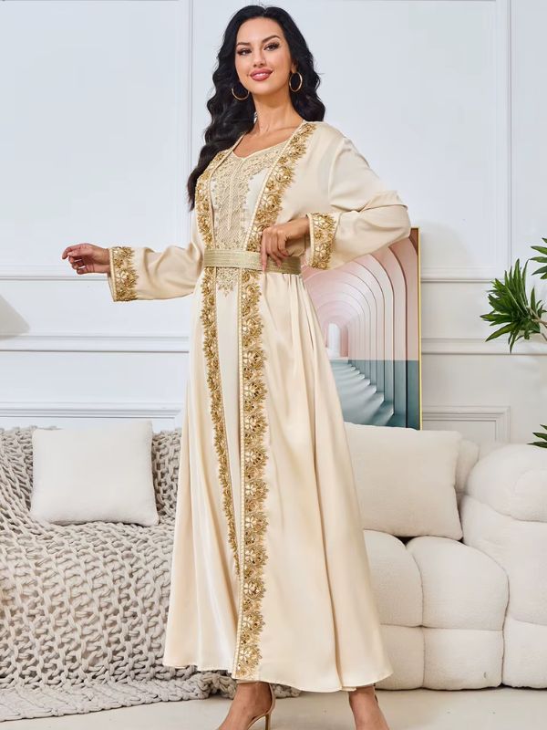 Une femme debout en caftan beige décorée de broderies dorées