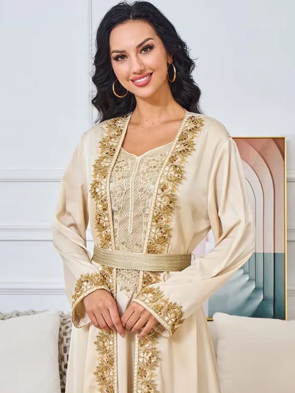 Une femme debout en caftan beige décorée de broderies dorées