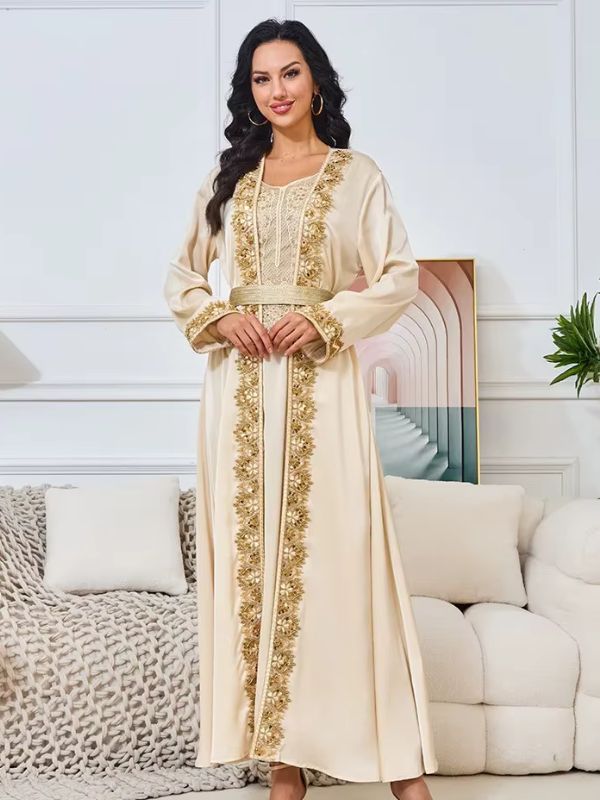 Une femme debout en caftan fluide avec ceinture et broderies raffinées