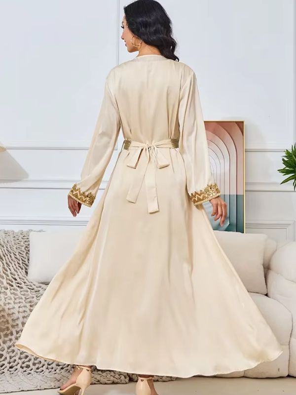 Une femme vue de dos en caftan satinée beige avec nœud à la taille