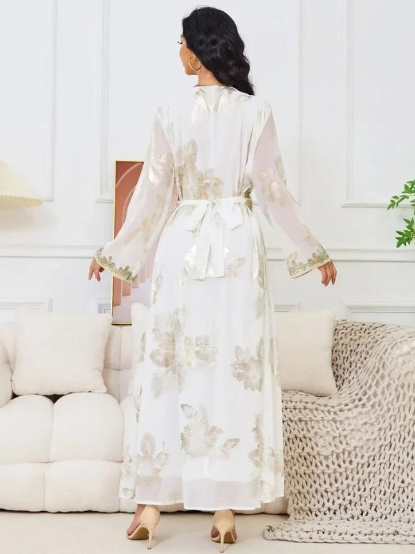 Une femme se trouve de dos, elle est vêtue d&#39;un caftan aux détails minutieux et artistique digne de la tradition marocaine, elle porte des talons, elle a aussi les cheveux noires et des boucles d&#39;oreilles rondes