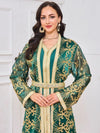 Une femme porte un caftan marocain vert émeraude à manches longues, accompagné d’une ceinture assortie ornée de détails perlés