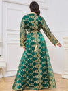 Une femme de dos porte un caftan marocain vert émeraude long et fluide, richement orné de broderies dorées sur le buste et les manches