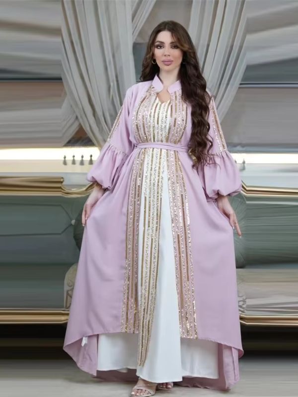 Femme portant un caftan lavande à sequins dorés sur une robe longue blanche, dans un décor élégant.