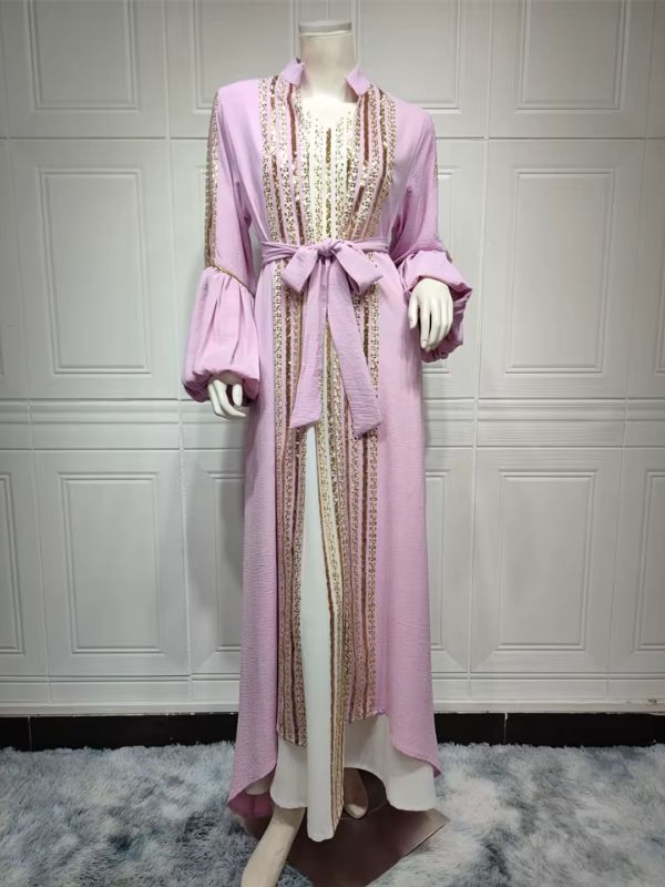 Femme portant un caftan lavande à sequins dorés sur une robe longue blanche, dans un décor élégant.