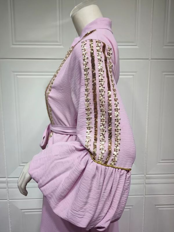Vue de profil d'un caftan lavande, manches bouffantes ornées de rangées de sequins dorés.